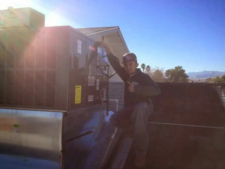 HVAC technician performing Heat Pump Repair on a rooftop unit in Wall